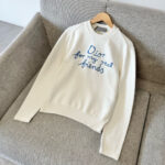 Felpa bianca con ricamo blu Dior for my real friends su poltrona moderna e confortevole.