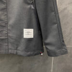 Giacca moderna grigia con tasca zip, dettaglio rosso e tag minimalista, stile sofisticato e pratico.