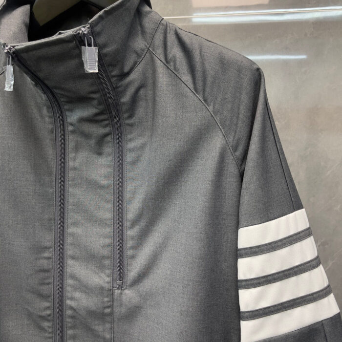 Giacca sportiva grigia moderna con strisce bianche e zip frontale, stile minimalista e versatile.