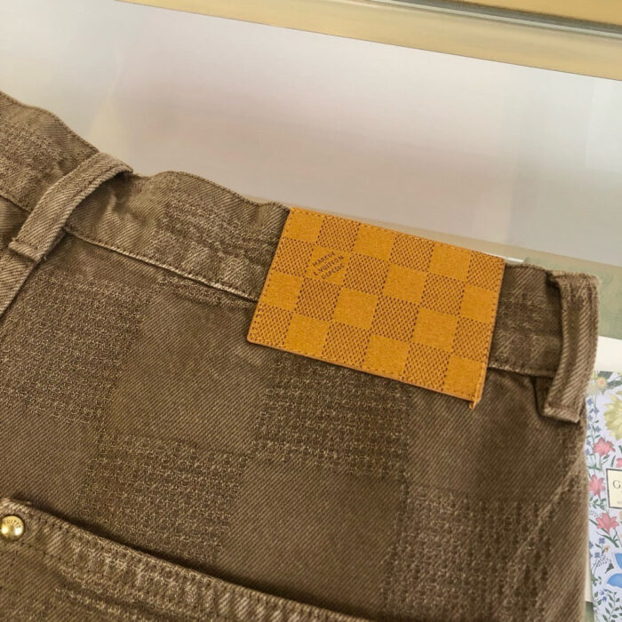 Pantaloni marroni eleganti con etichetta a quadri e bottoni metallici, stile moda sofisticata.