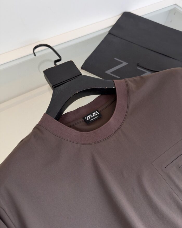 Maglietta minimalista in tonalità terra con taschino, su appendiabiti nero con logo Z.