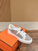 Sneaker moderna grigia con dettagli in pelle bianca su scatola arancione vibrante.