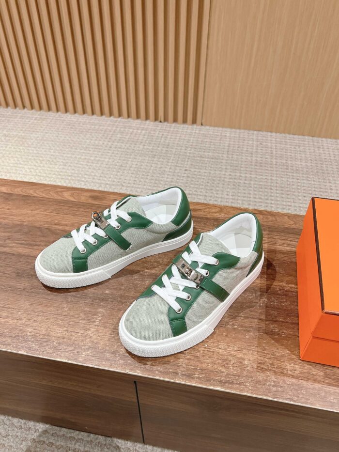 Sneakers verde chiaro e bianco su superficie in legno, con scatola arancione elegante e design moderno.