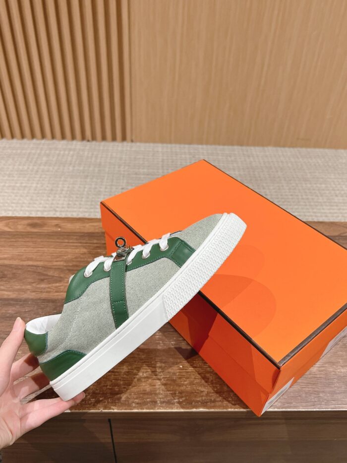 Sneaker moderna grigia e verde con scatola arancione su sfondo in legno e parete decorativa.