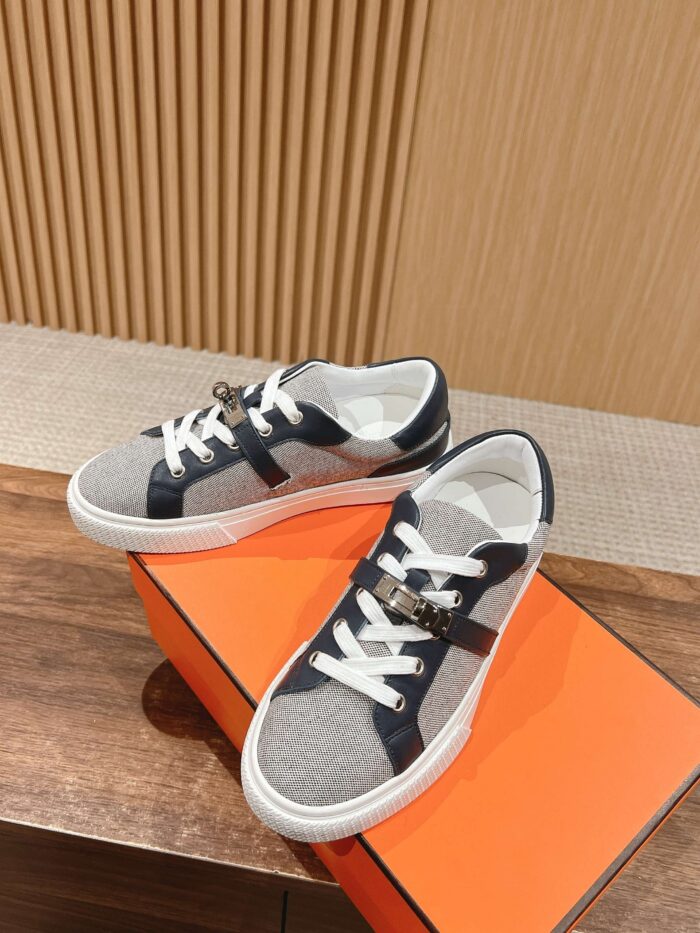 Sneakers grigio navy su scatola arancione, stile moderno e eleganza casual, ambientazione raffinata.