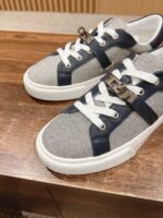 Sneakers moderne grigie e navy con dettagli metallici, suola in gomma bianca, stile contemporaneo.