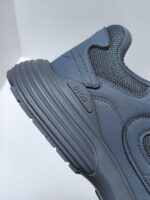 Sneaker grigia moderna con suola a rilievo, dettagli in mesh e logo minimalista elegante.
