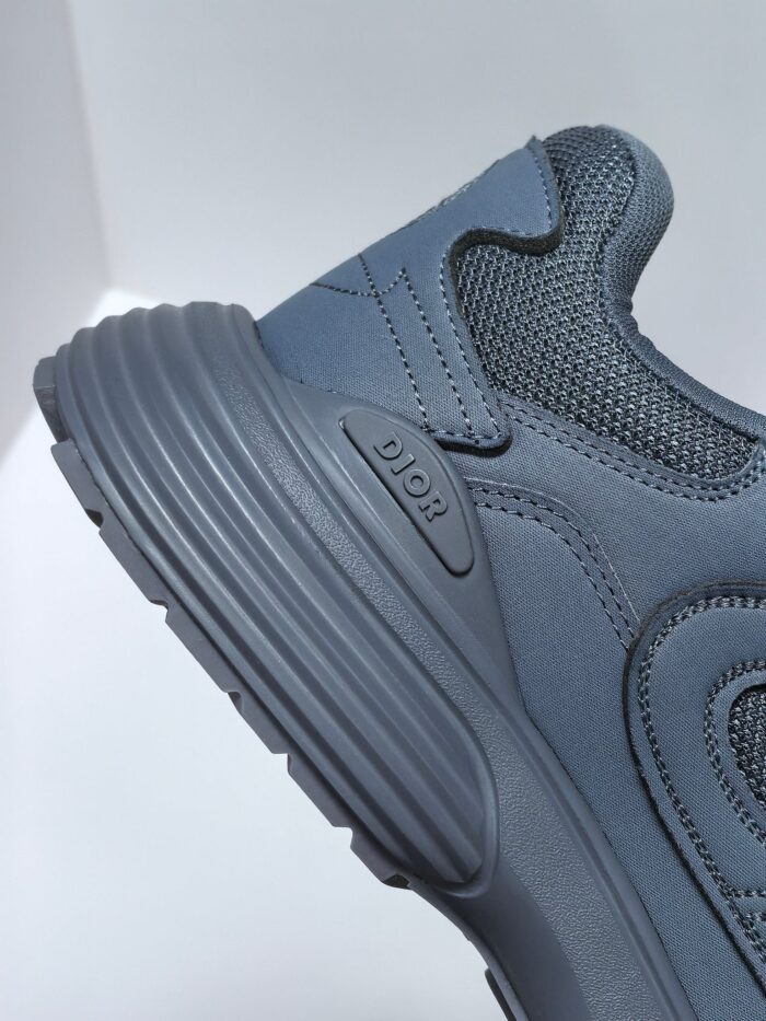 Sneaker grigia moderna con suola a rilievo, dettagli in mesh e logo minimalista elegante.