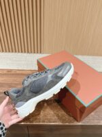 Sneaker moderna grigia con suola bianca, in mano, sfondo elegante con scatola e dettagli raffinati.