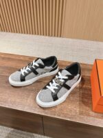 Sneaker grigia elegante con dettagli neri e lacci bianchi su sfondo in legno raffinato.
