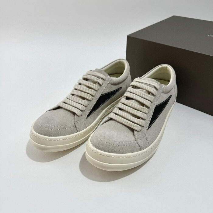 Scarpe da ginnastica in suede beige con dettagli neri e suola bianca minimalista.