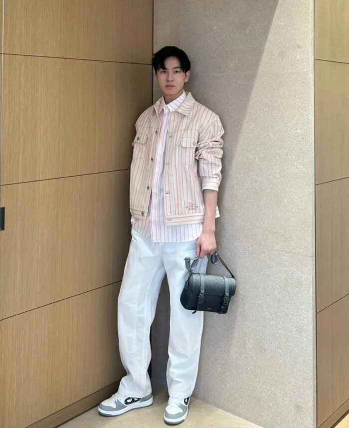Uomo giovane in stile casual chic con giacca a righe, pantaloni bianchi e sneakers moderne