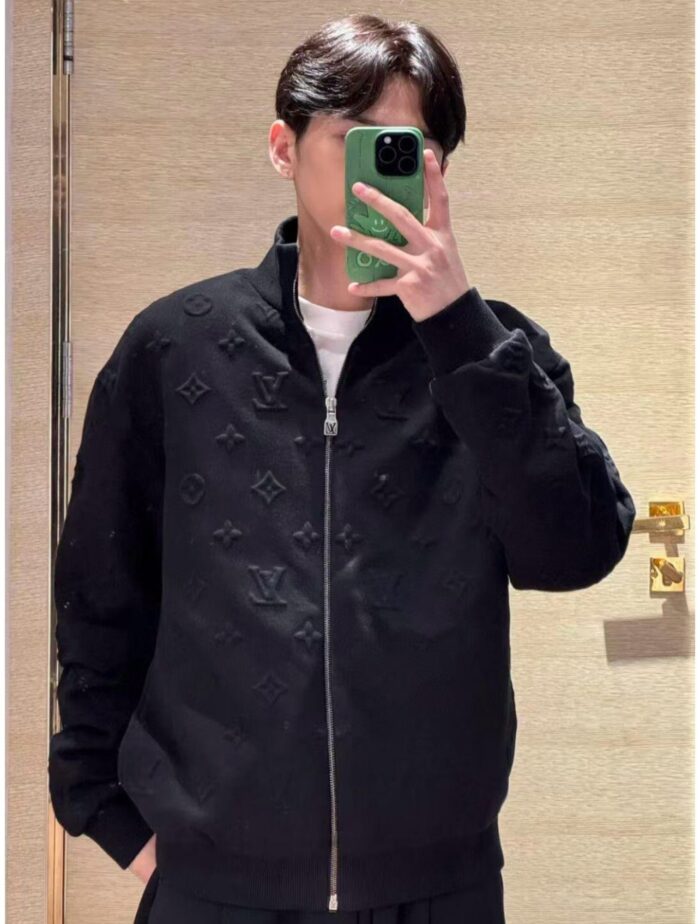Uomo con giacca nera e smartphone verde scatta selfie in interno elegante.