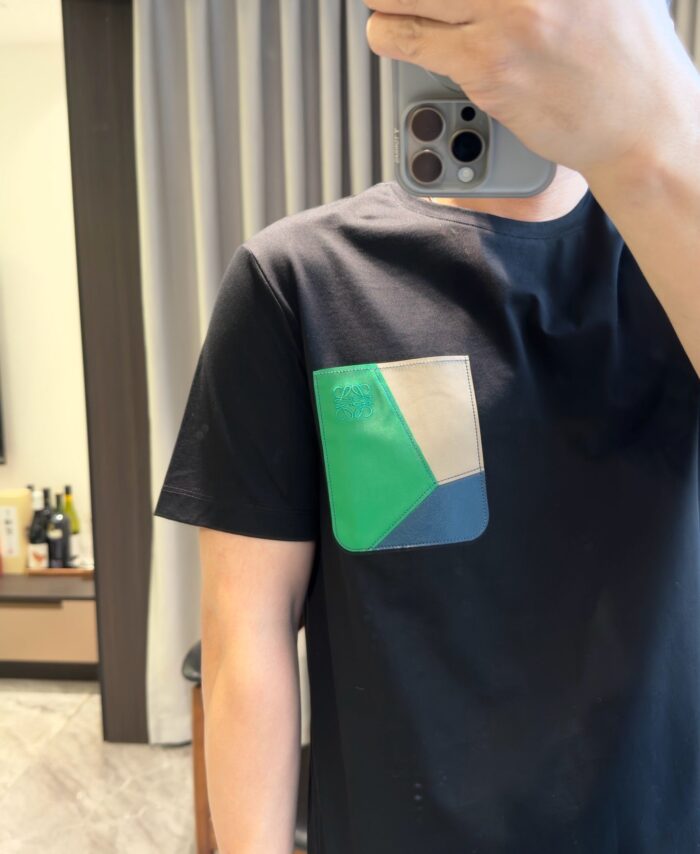Selfie con T-shirt nero e tasca colorata, stile moderno e ambiente elegante.
