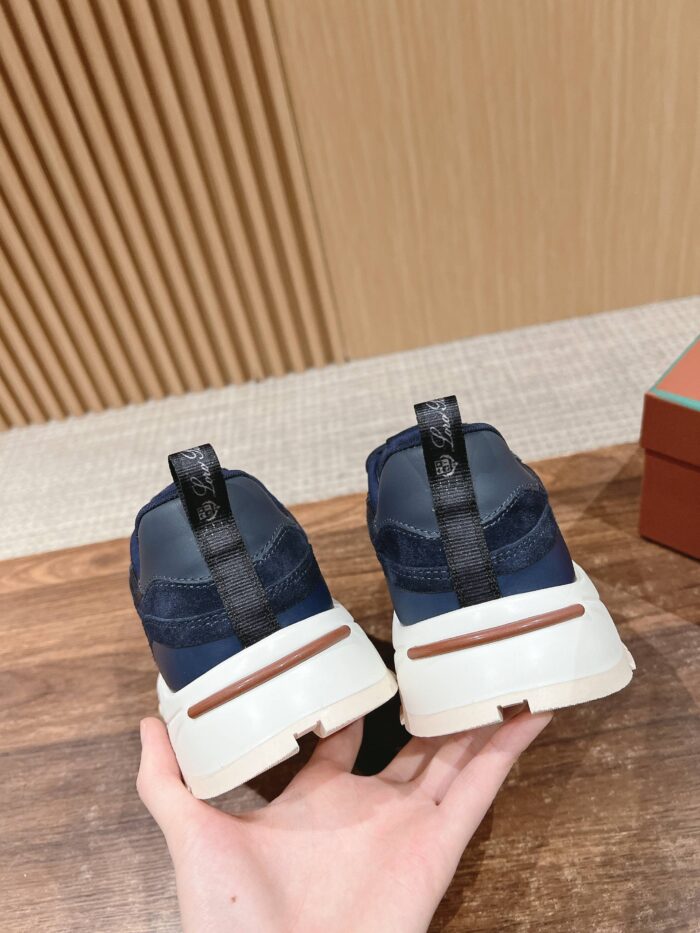 Sneakers navy e bianco con suola marrone, tirante nero, stile sportivo e comfort quotidiano.