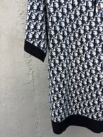 Vestito navy e bianco con logo geometrico, maniche corte e dettaglio nero, stile elegante e moderno.