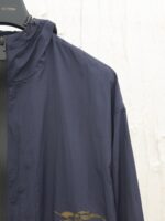 Giacca leggero navy con logo dorato e cappuccio invisibile, stile casual e pratico.