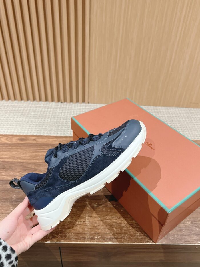 Sneaker navy e bianco elegante in suede e mesh, con packaging raffinato su tavolo in legno.