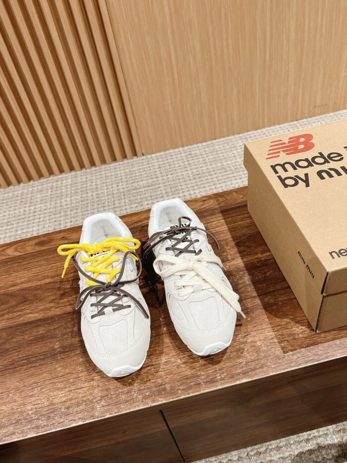 Scarpe New Balance moderne con lacci colorati, packaging minimalista e sfondo caldo e elegante.