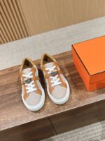 Sneakers beige e arancioni su tavolo di legno, con scatola elegante opzionale.