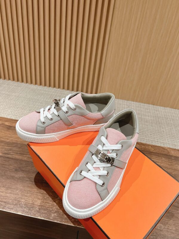 Sneakers pastello eleganti su scatola arancione, stile casual e sportivo, su sfondo in legno.