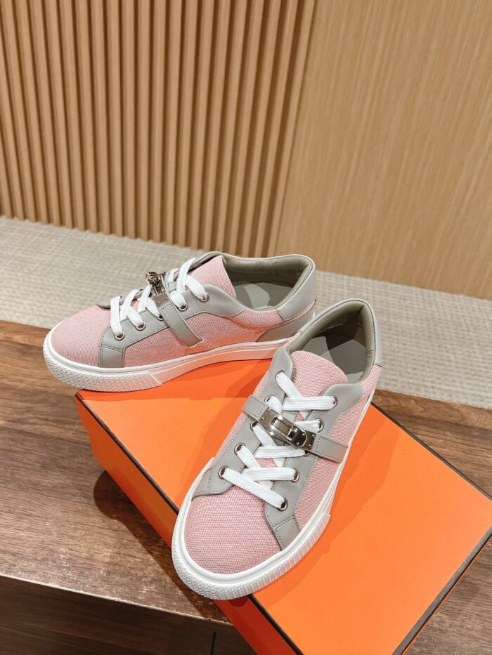 Sneakers pastello eleganti su scatola arancione, stile casual e sportivo, su sfondo in legno.