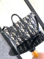 Borsa elegante in tessuto con logo, manici in pelle e tracolla regolabile, stile moderno e versatile.