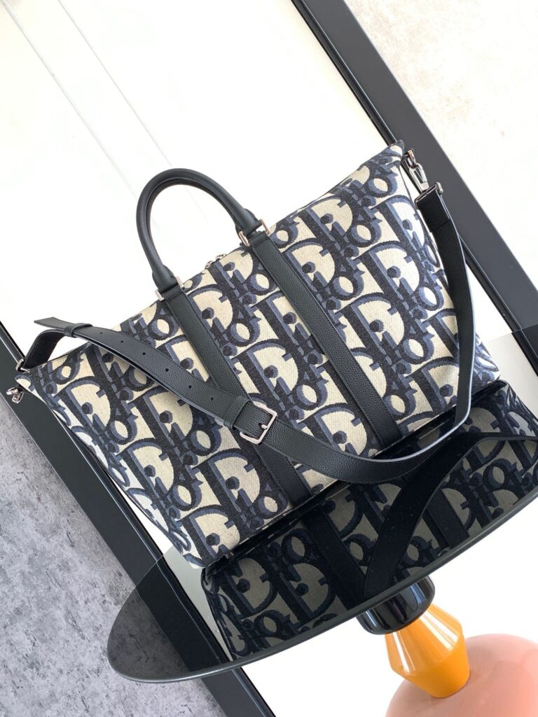 Borsa elegante in tessuto con logo, manici in pelle e tracolla regolabile, stile moderno e versatile.