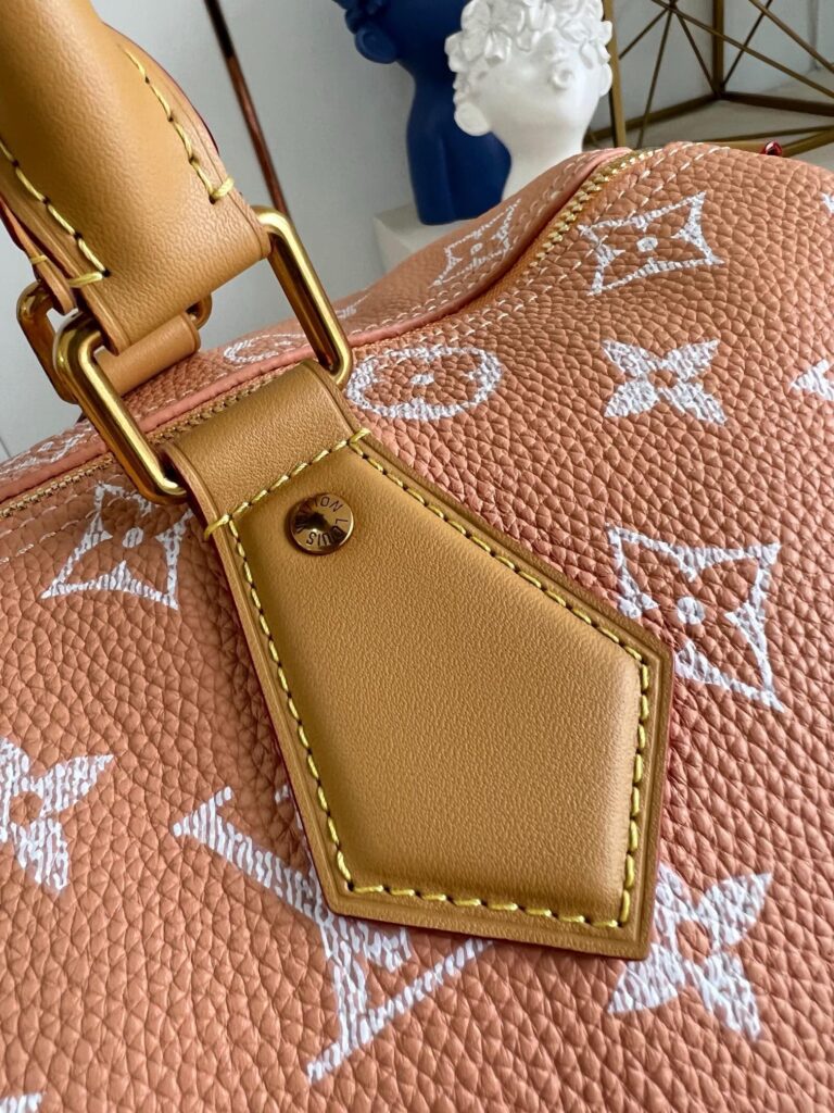Borsa di lusso in pelle pesca con dettagli dorati e stile elegante.