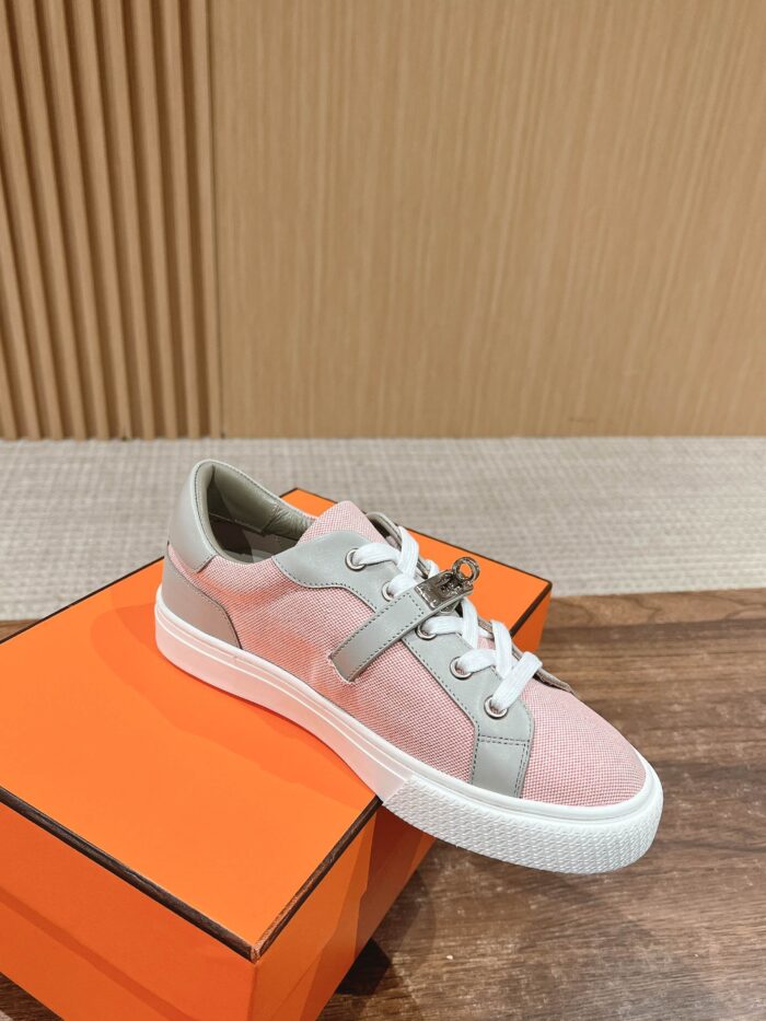 Sneaker rosa e grigia su scatola di lusso arancione, stile moderno e sofisticato.