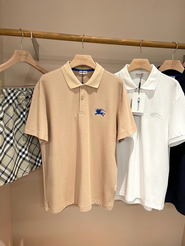Esposizione di polo shirt eleganti in beige, bianco e navy su appendiabiti in legno.