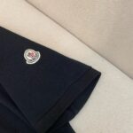 Manica di giacca scura con logo circolare bianco e rosso, stile elegante e minimalista.