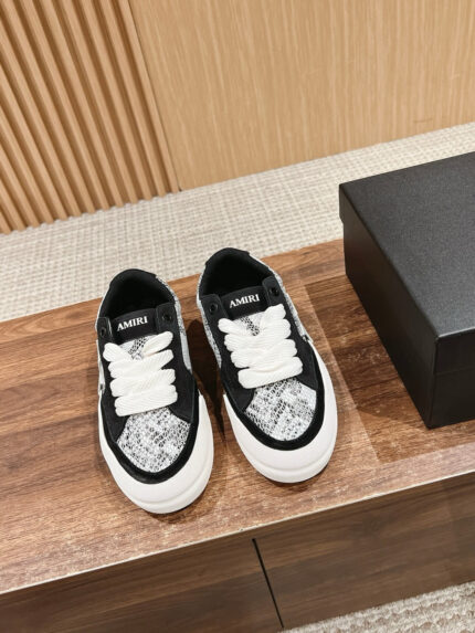 Sneakers nero e bianco con motivo serpente, stile moderno e urbano su superficie in legno.