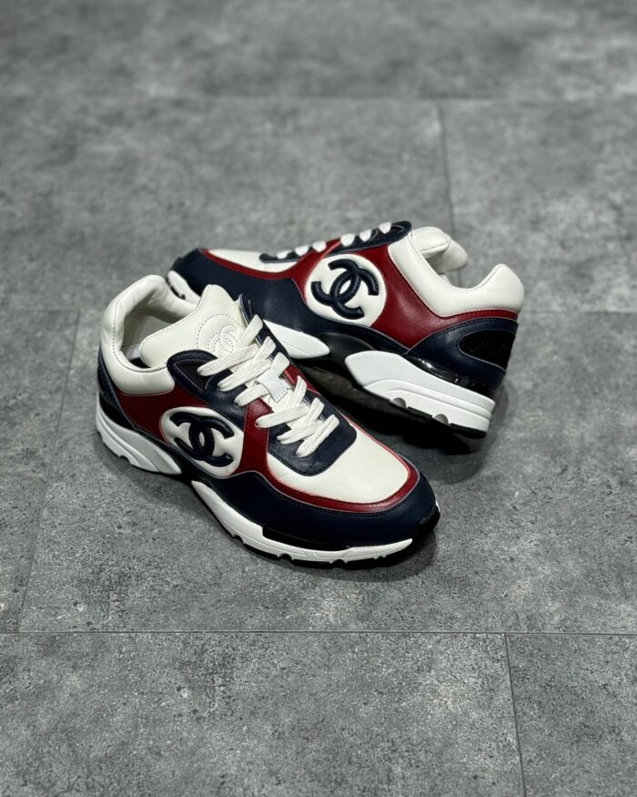 Sneakers eleganti bianche, blu navy e rosso con logo di lusso e suola testurizzata.