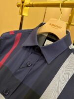 Camicia Burberry moderna con strisce colorate su appendiabiti dorato di lusso.