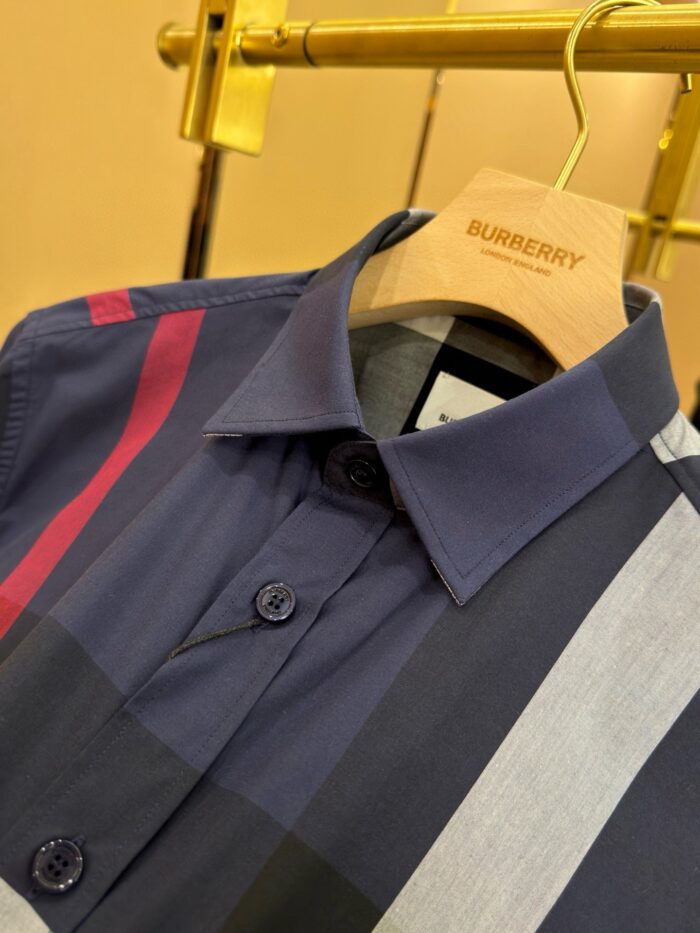 Camicia Burberry moderna con strisce colorate su appendiabiti dorato di lusso.
