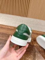 Sneaker bianca con dettagli verdi, elegante e sportiva, tenuta in mano, su sfondo di legno.
