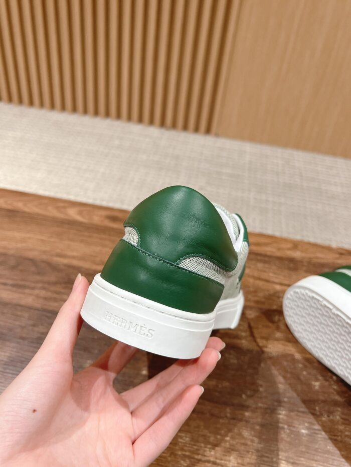 Sneaker bianca con dettagli verdi, elegante e sportiva, tenuta in mano, su sfondo di legno.