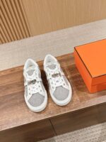Sneakers bianche e grigie di alta moda su tavolo in legno con scatola arancione elegante.