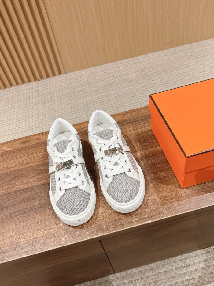 Sneakers bianche e grigie di alta moda su tavolo in legno con scatola arancione elegante.