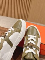 Sneakers bianche eleganti con dettagli verde oliva, fibbia metallica e stile moderno.