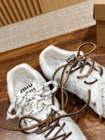 Sneakers bianche moderne con lacci contrasto, stile casual e detail di marca, su superficie in legno.