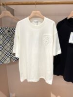 Outfit estivo casual con t-shirt bianca, pantaloncini a quadri e maglia nera minimalista.