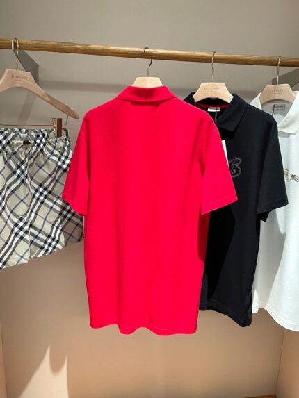 Outfit estivo con polo rossa, shorts a quadri e polo bianca e nera su appendiabiti elegante.