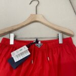 Pantaloncini da spiaggia rossi in tessuto lucido, elastico con cordino e logo, adatti allestate.