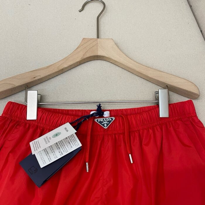 Pantaloncini da spiaggia rossi in tessuto lucido, elastico con cordino e logo, adatti allestate.