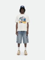 giovane uomo in streetwear estivo con t-shirt tropicale, shorts cargo e cappellino navy