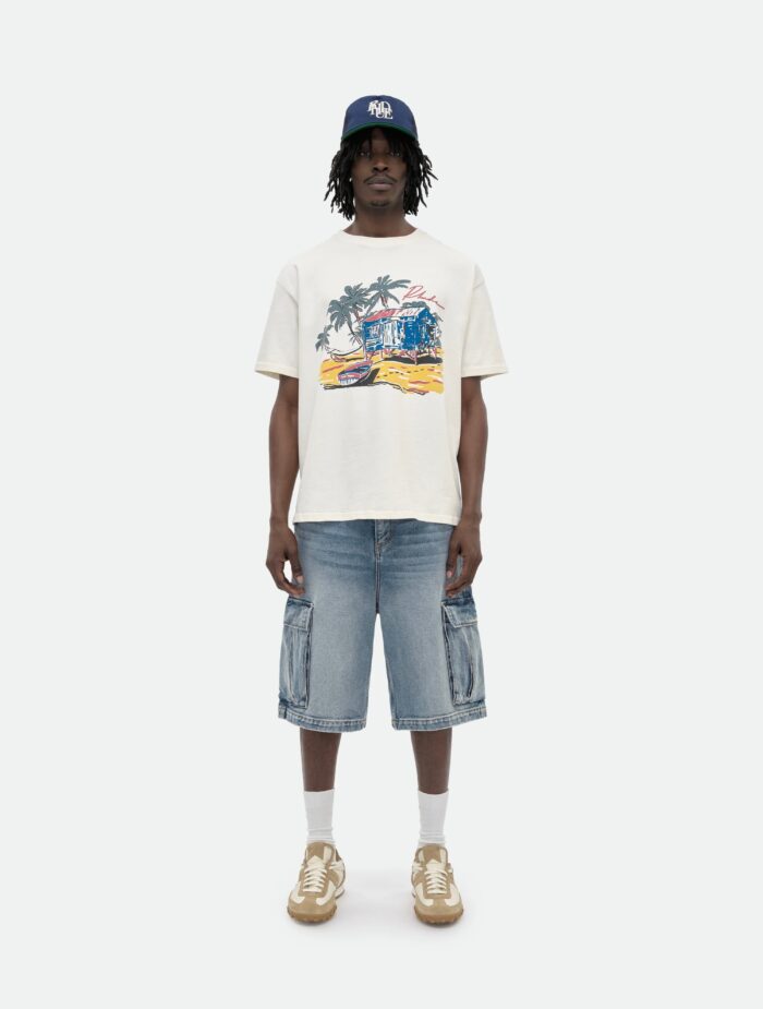 giovane uomo in streetwear estivo con t-shirt tropicale, shorts cargo e cappellino navy