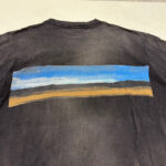 Maglietta nera con paesaggio al tramonto, stile impressionista, tessuto vintage, casual e artistico.