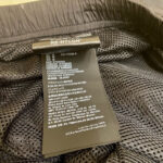 Etichetta di vestito in RE-NYLON riciclato con istruzioni e dettagli sostenibili.